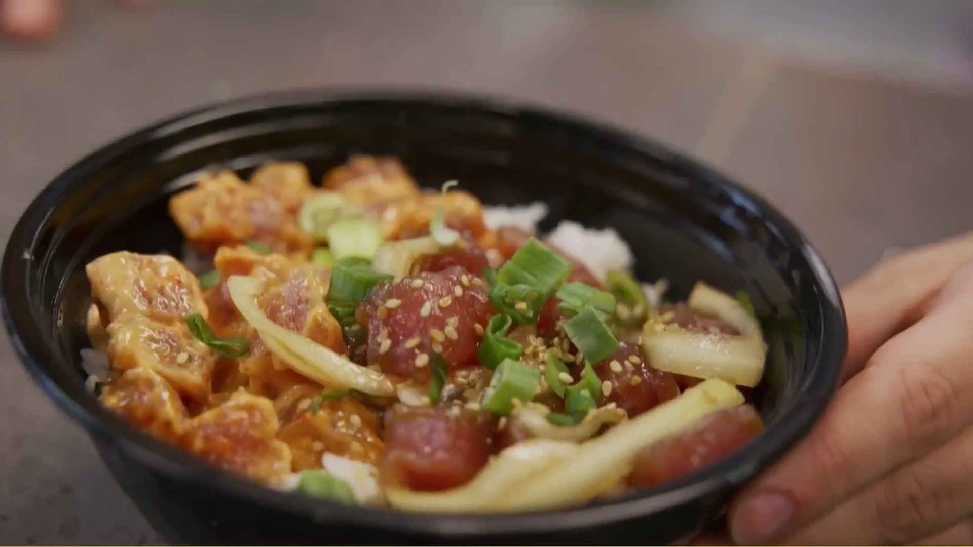 A fresh poke bowl being opened and sauced at Generations Kitchen
